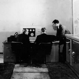 Turing inspeccionando el Ferranti Mark I, uno de los primeros ordenadores de la historia, en cuyo diseño y desarrollo fue protagonista.