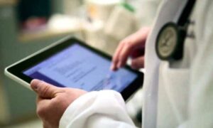 Imagen de un médico empleando un dispositivo electrónico para conectar con pacientes.
