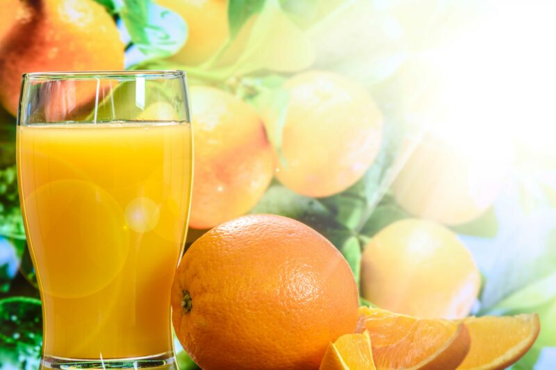 Fotografía representando las propiedades antioxidantes del zumo de naranja con naranjas al fondo.