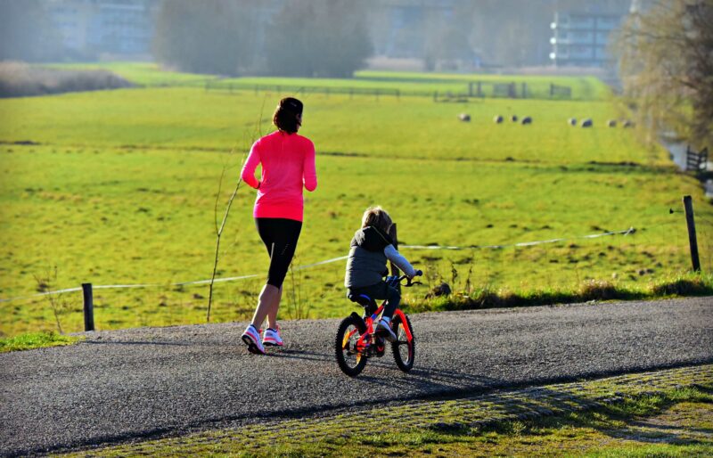 Imagen de una mujer y una niña haciendo ejercicio al aire libre.